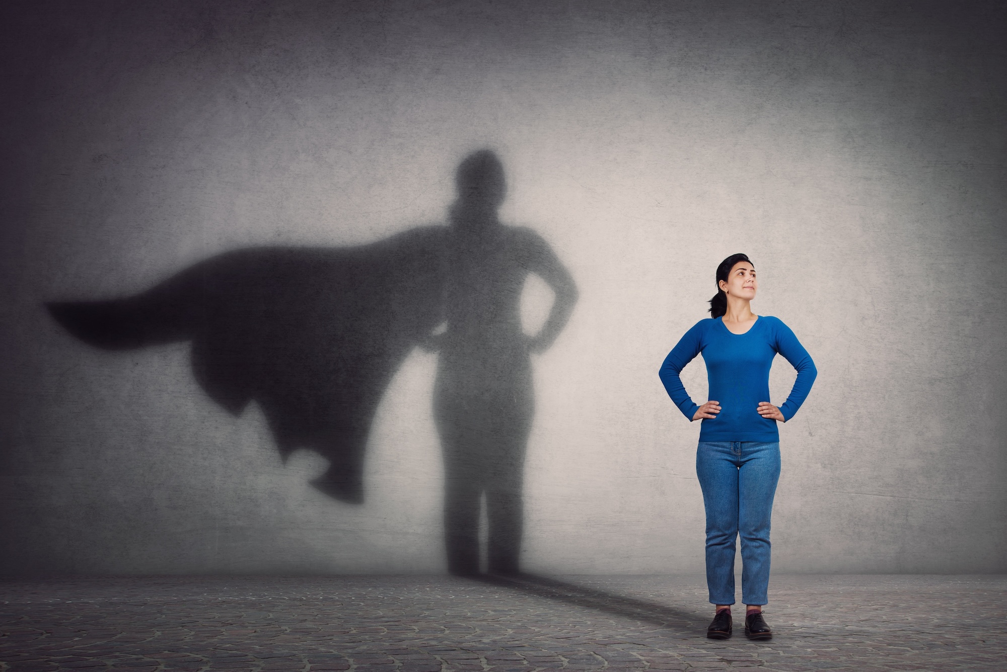 Woman in blue shirt with a super hero cape shadow